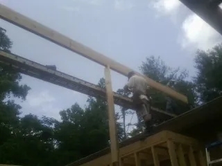 Carpenter setting a ridge beam over a new addition frame — Ice Dam Removal by Roofing Brothers in Springfield Gardens