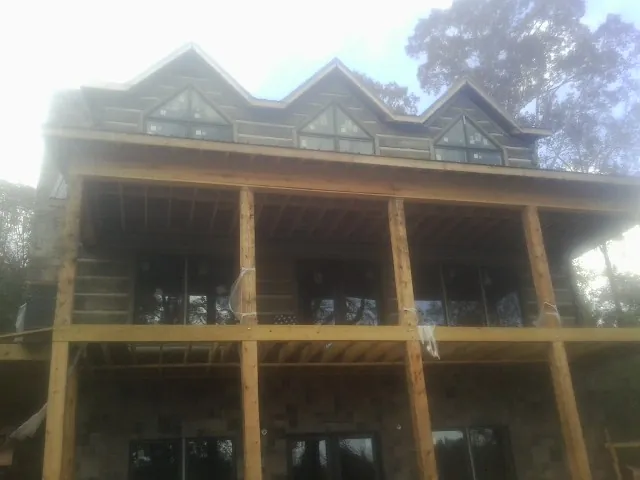 Dormers and porch framing on a large log home under construction — Roof Coating work by our crew in Springfield Gardens