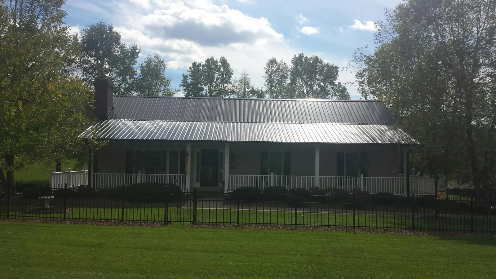 Gray metal roof on a brick ranch with a full width front porch — Gutter Guard Installation work by our crew in Springfield Gardens