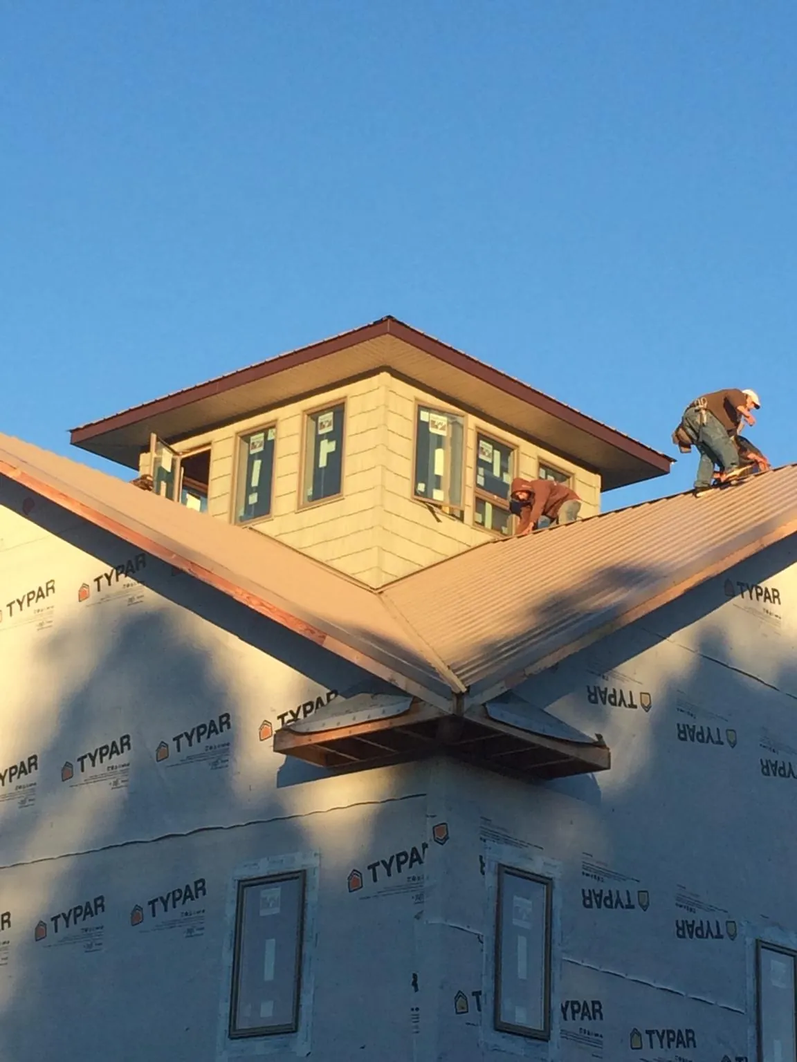 Roofers working around a rooftop cupola on a new metal roof at sunset — Roof Waterproofing in Springfield Gardens by Roofing Brothers